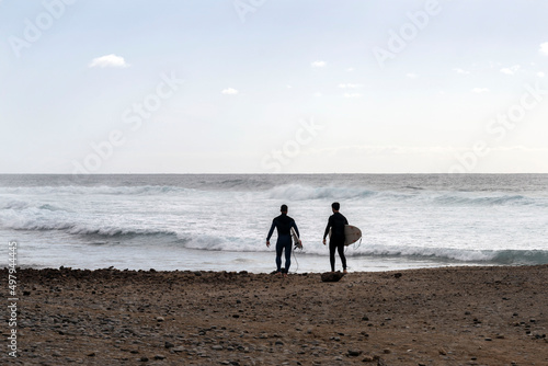 two surfers go to the ocean on the island of Tenerife