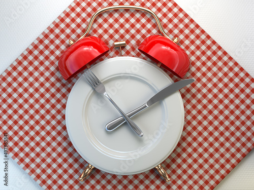 Plate as alarm clock with knife and fork in a restaurant. Time to eat, intermittent fasting, lunch, diet, and weight loss concept