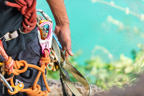 Confidence Asian man climber preparing safety equipment for climbing rock mountain at tropical island. Strong male enjoy outdoor active lifestyle and extreme sport climbing on summer beach vacation