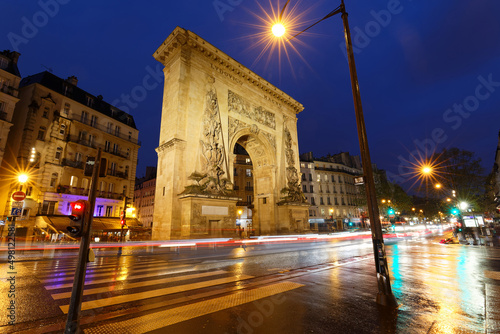 Porte Saint-Denis at rainy night . It is a Parisian monument located in the 10th arrondissement of Paris, France.