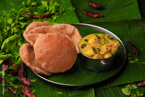 south indian famous breakfast poori or puri with potato curry served in a plate with banana leaf closeup with selective focus and blur