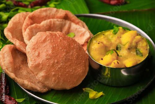 south indian famous breakfast poori or puri with potato curry served in a plate with banana leaf closeup with selective focus and blur