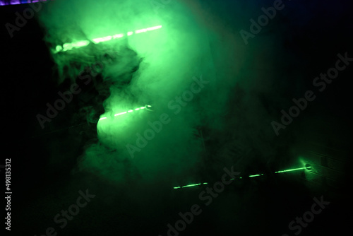 Bright green neon laser lights illuminate the darkness creating lines.