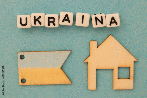 Napis Ukraina leżący nad drewnianym domem i flagą Ukrainy - symboliczne znaczenie