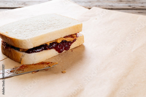 Close-up of peanut butter and jelly sandwich on brown paper with table knife at table