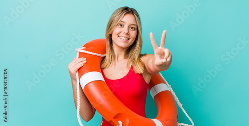 pretty blonde woman smiling and looking friendly, showing number two. lifeguard concept