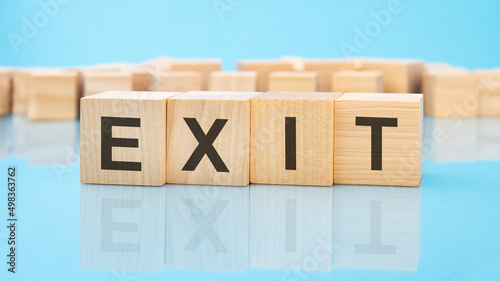 letters Exit made with wood building blocks. blue background. business concept