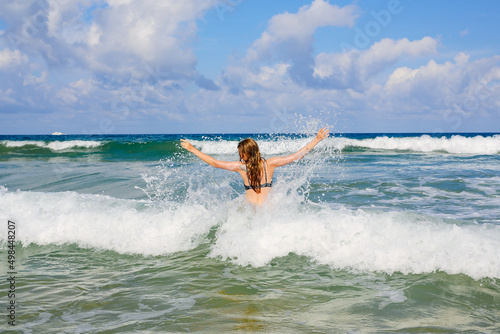 The girl bathes in the sea and enjoys the waves. sunny day
