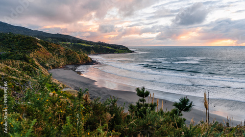 Beautiful view of the cliffs and seascape against dusk sky at Ngarunui Beach, Raglan, New Zealand