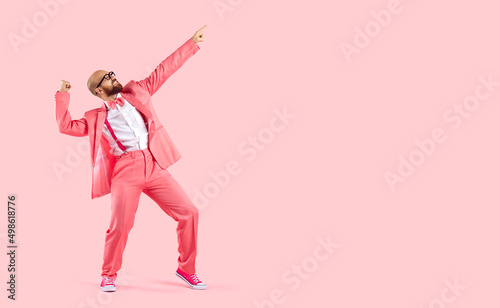 Cheerful successful man dancing funny making movements winner isolated on pink background. Funny man in pink formal suit celebrates his success having fun at copy space. Full length. Banner.