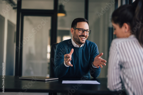 Smiling businessman explaining something to a female client.