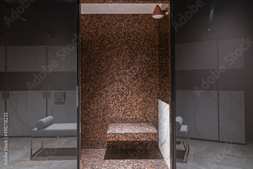 Elegancka, luksusowa i nowoczesna łazienka z prysznicem i deszczownicą. Ciekawie prezentująca się na ścianie mozaika o ciepłej barwie.