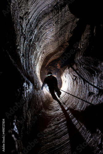 Man on the rope climbing in dark cave 