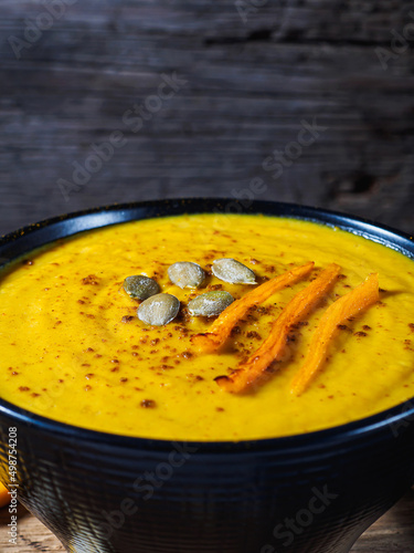 Pumpkin and carrot and chickpeas Cream soup on rustic wooden table.
