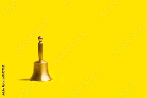 Campana de bronce con mango sobre un fondo amarillo aislado y aislado. Vista de frente y de cerca. Copy space