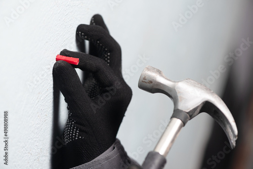 Worker inserts a plastic dowel into the wall close up.