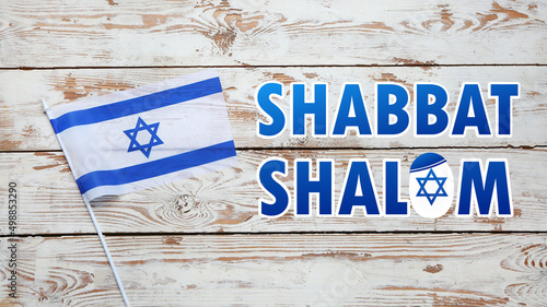 Flag of Israel and text SHABBAT SHALOM on wooden background