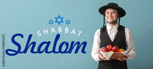 Hasidic Jewish man with basket of fruits and text SHABBAT SHALOM on blue background