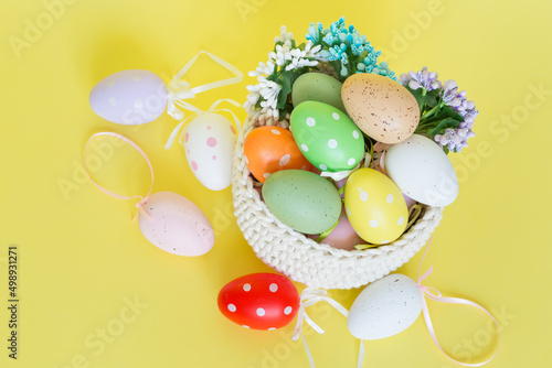 Drkoracje wielkanocne, koszyk, kolorowe jajka pisanki, na żółtym tle