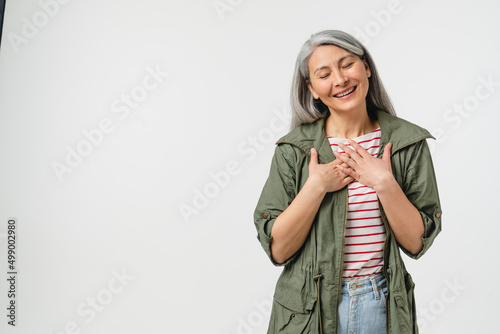 Pleased touched with a compliment caucasian mature middle-aged woman in casual clothes listening to praise isolated in white background