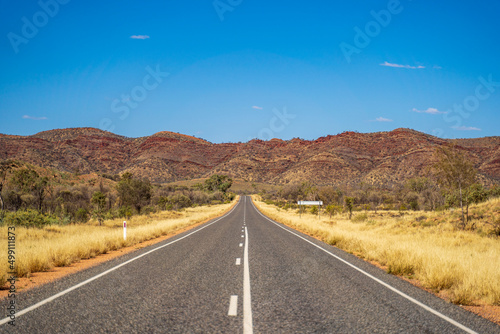 Outback road near Alice Springs with the East Macdonnell Range on the horizon. Northern Territory, Australia.