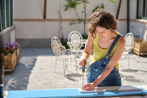young woman in the garden assembling a piece of furniture