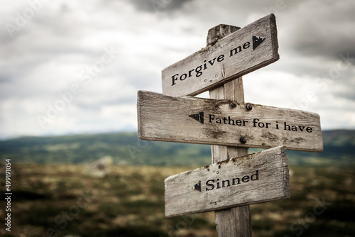 forgive me father for i have sinned text quote written in wooden signpost outdoors in nature. Moody theme feeling.