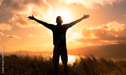 It's a beautiful life! Man standing in a field at sunset having feelings of freedom, hope, and happiness 