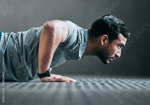 Forward focus. Cropped shot of a handsome young male athlete doing pushups against a grey background.