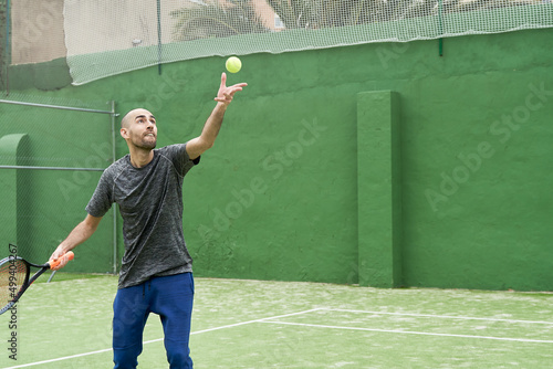 Amateur tennis player learns to serve at court with ball and racket