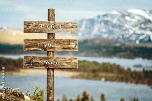 protect your peace text quote written on wooden signpost outdoors in nature with lake and mountain scenery in the background. Moody feeling.