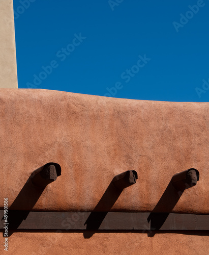 close up of adobe house against blue sky in Santa fe New Mexico with water run off drains abstract design of Santa Fe home architecture shapes and shadows while on holiday in Santa Fe vertical format