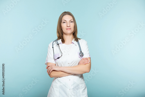Beautiful female doctor with a stethoscope with crossed arms on a blue background. healthcare concept.