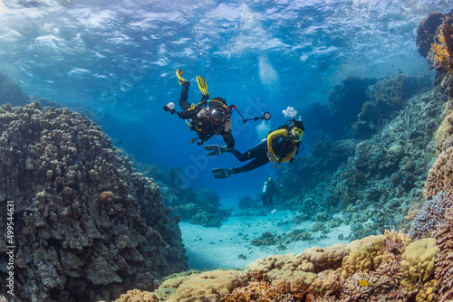 Underwater exploration. Divers dive on a tropical reef with a blue background and beautiful corals.