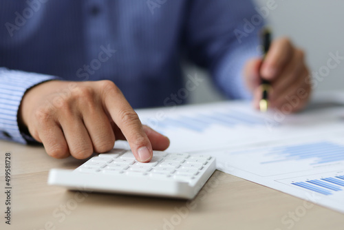 Accountant or banker working process, a Businessman using a calculator to calculate the numbers of statistic business profits growth rate on documents graph data in the desk office.