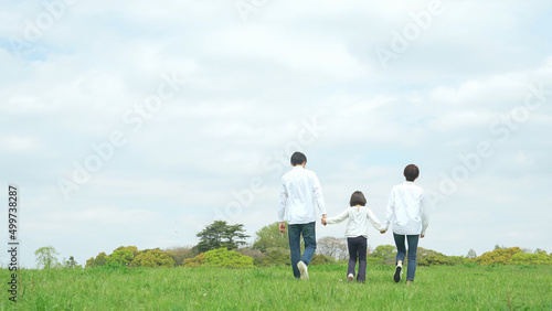 手を繋いで草原を歩く親子 ファミリー 子育て 自然環境