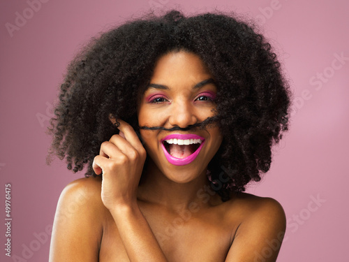 Nothing more attractive than a sense of humor. Studio shot of an attractive young woman posing against a pink background.