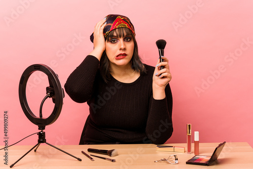 Young makeup artist woman doing a makeup tutorial isolated on pink background being shocked, she has remembered important meeting.