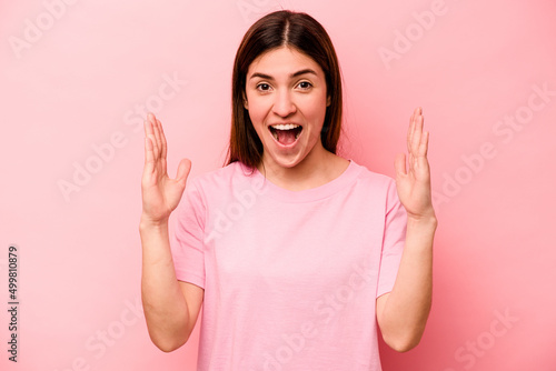 Young caucasian woman isolated on pink background receiving a pleasant surprise, excited and raising hands.