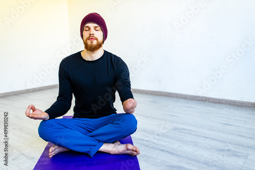 amputees handisport young man doing yoga meditation with closed eyes indoors at home