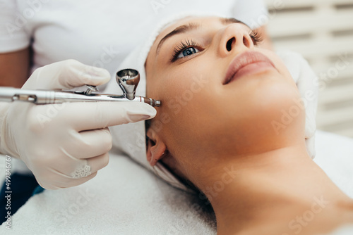 Beautiful brunette getting oxygen face therapy in a beauty salon. Professional skin care treatment.