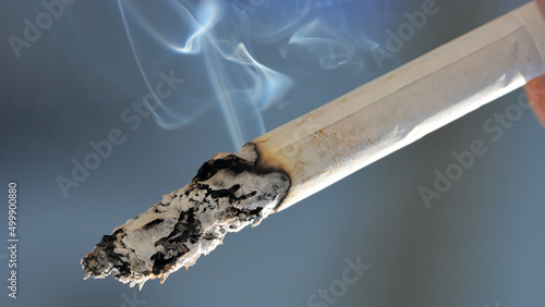 Papieros z płomieniem na końcu i unoszącym się dymem szkodliwym dla zdrowia.