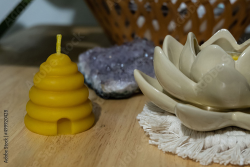 A beehive votive shaped beeswax candle is displayed next to a crystal and flower shaped candle holder.