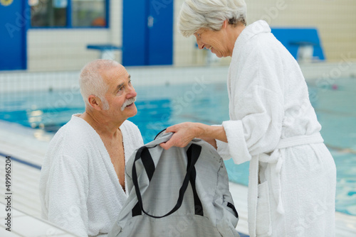 happy senior couple in bathrobe by resort pool