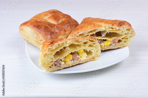 Ham and corn puff pastry, accompanied by sauce on a wooden background