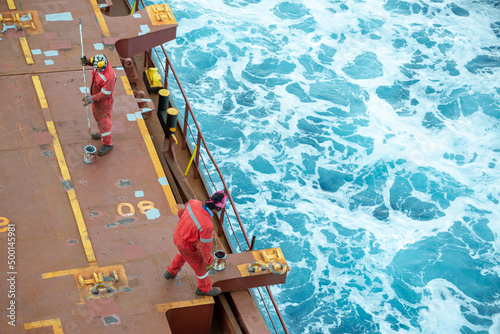 Seaman ship crew priming and derusting vessel deck for upcoming painting.