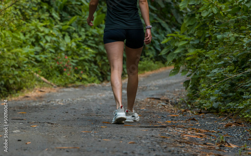 Sport girl walks across a green country road