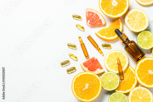 Vitamin C. Anti aging cosmetic. Fresh citrus fruits with serum bottles, ampoules and pills. Top view with copy space.