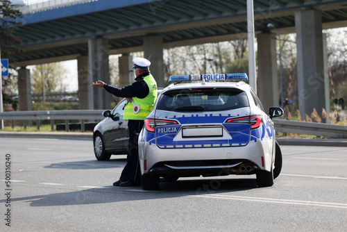  Policjant policji drogowej podczas kierowania ruchem z lizakiem do zatrzymywania pojazdów.