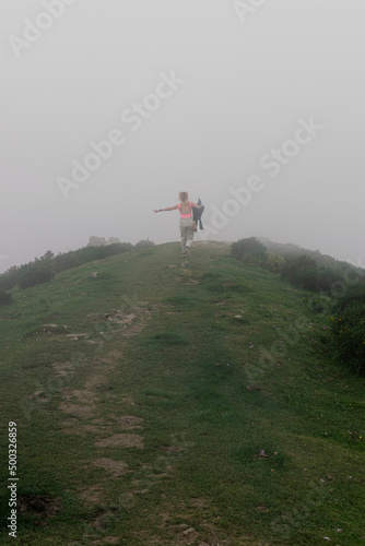 Chica joven corriendo entre la niebla en los lagos de Covadonga, Asturia